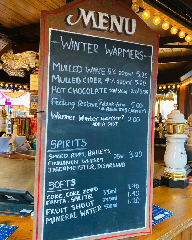 A Wooden Menu board propped u on the bar showing the drinks menu for the Kingston Christmas Market