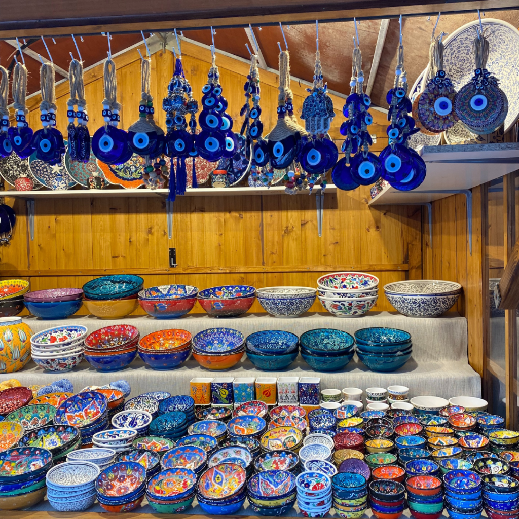 A wooden Christmas Market stall displaying colourful Turkish bowls in an assortment of colours and sizes. Hanging from the front of the stall is a display of Turkish Eyes.